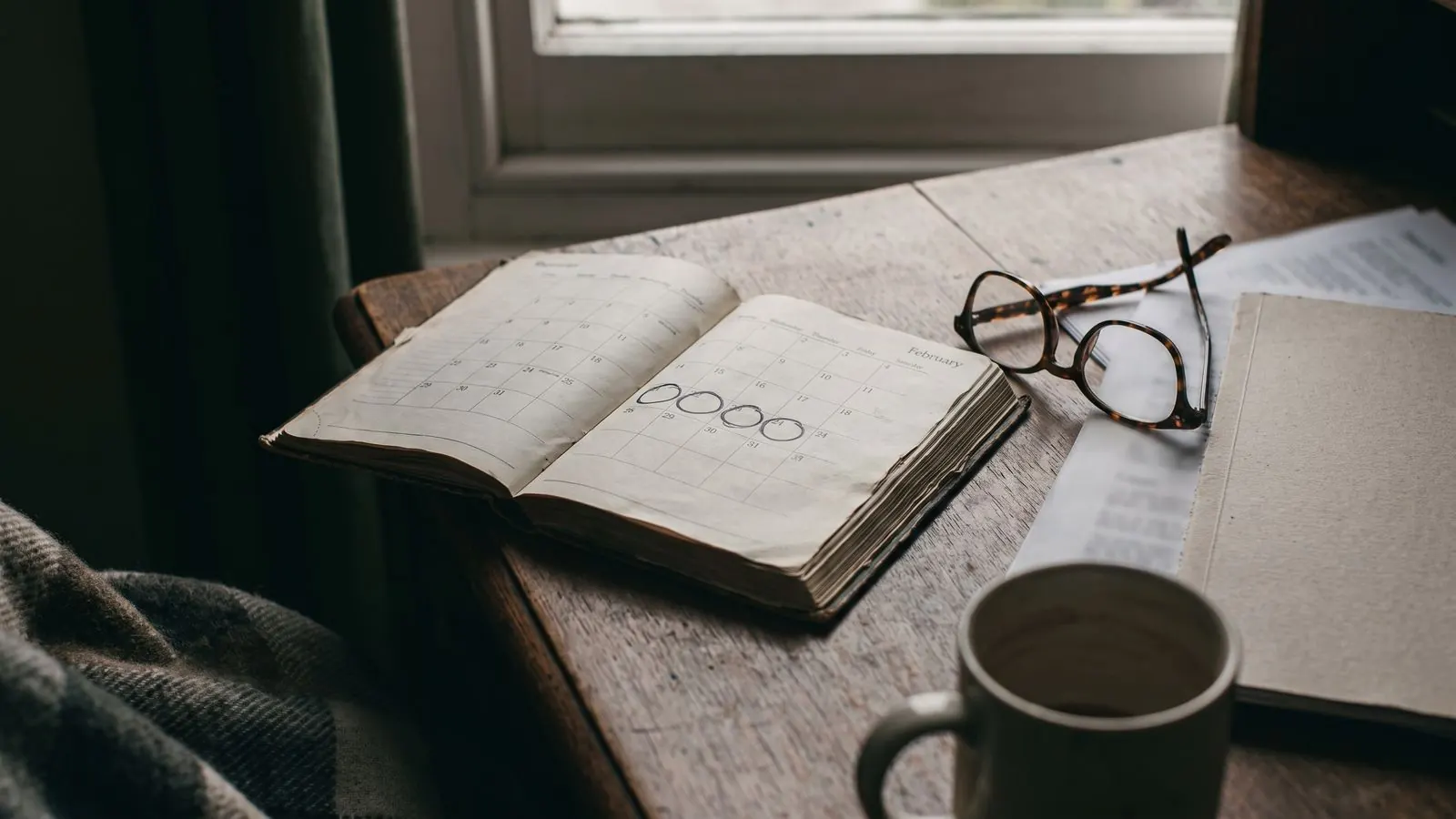A desk diary open at a month view with several dates ringed in pen