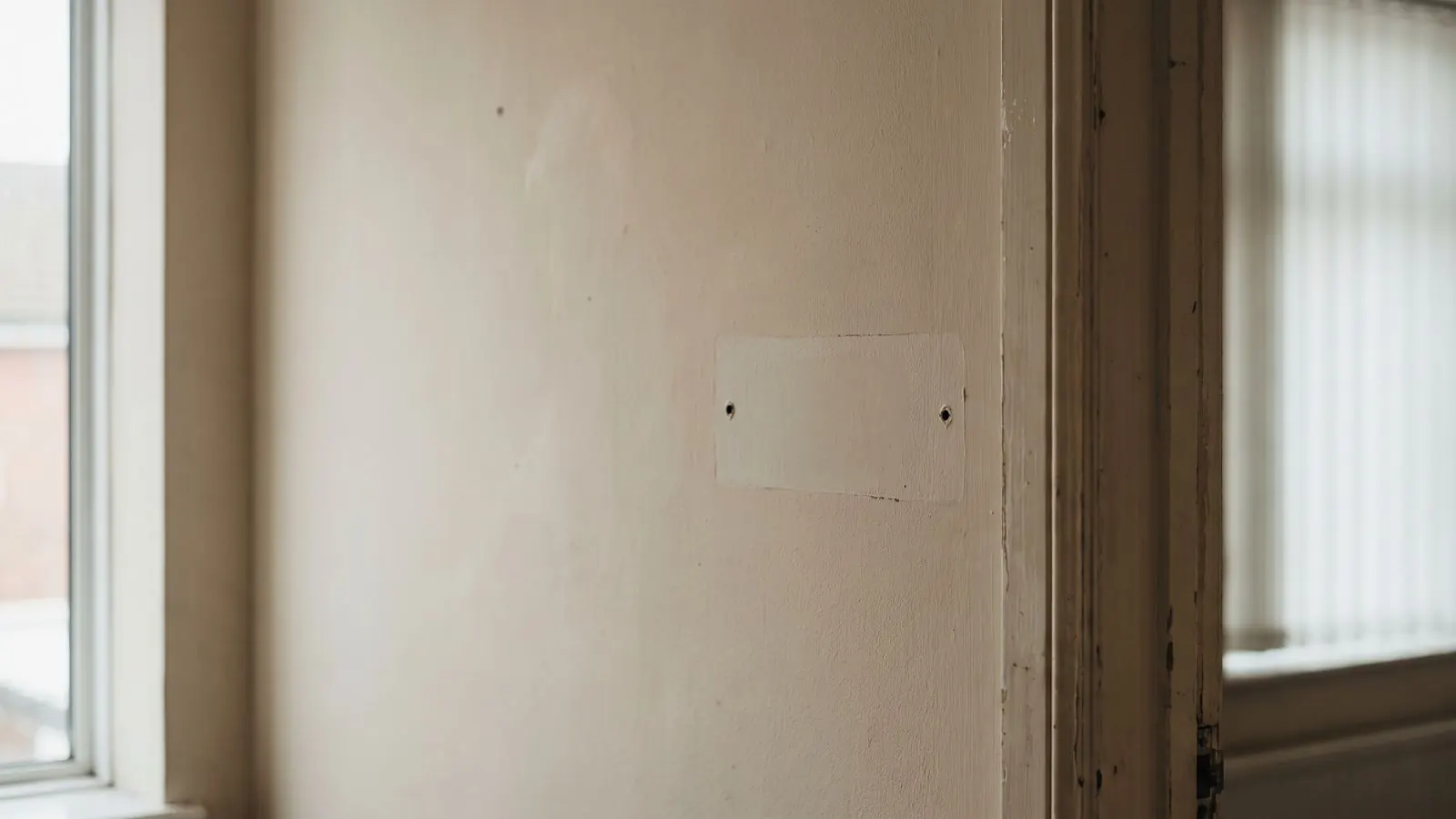 An office wall where a name plate has been taken down, leaving an unfaded rectangle
